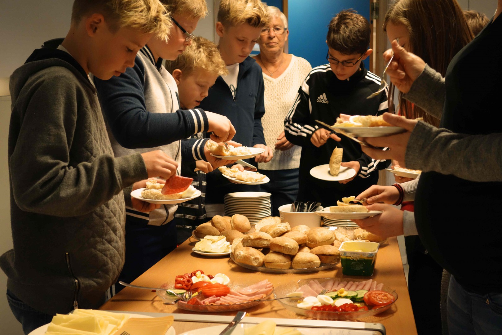 Elevane tar velvillig imot lunsjen, med bevertningen i bakgrunnen.